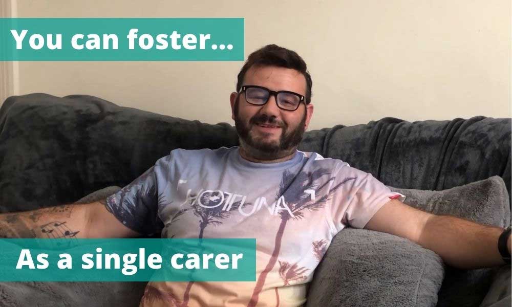 Man wearing glasses and smiling sat relaxing on sofa