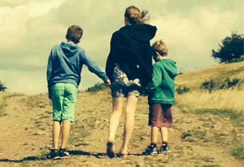 Three siblings holding hands walking on a beach