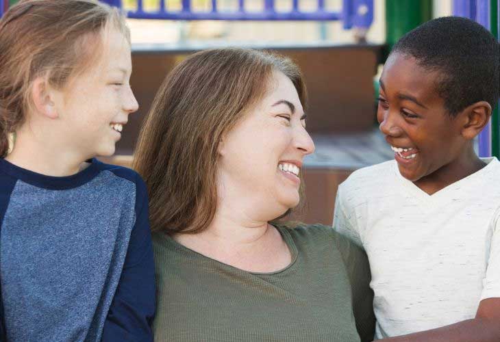 Foster carer stood between two children, all smiling