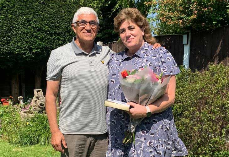 Foster carers Lynn and Saied side-by-side, Lynn holding bouquet of flowers