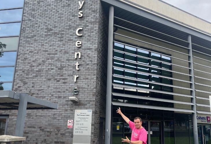 Foster carer, Phil pointing at Childwall Library exterior